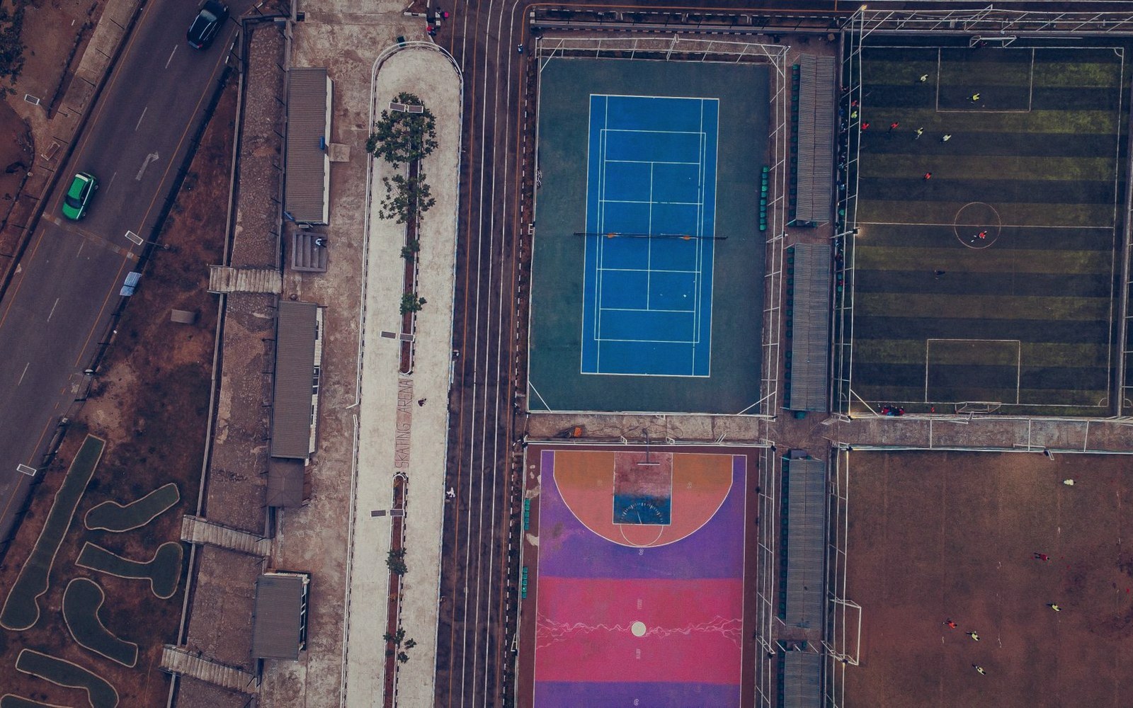 Aerial view of a tennis court, basketball court and soccer field beside a walking path