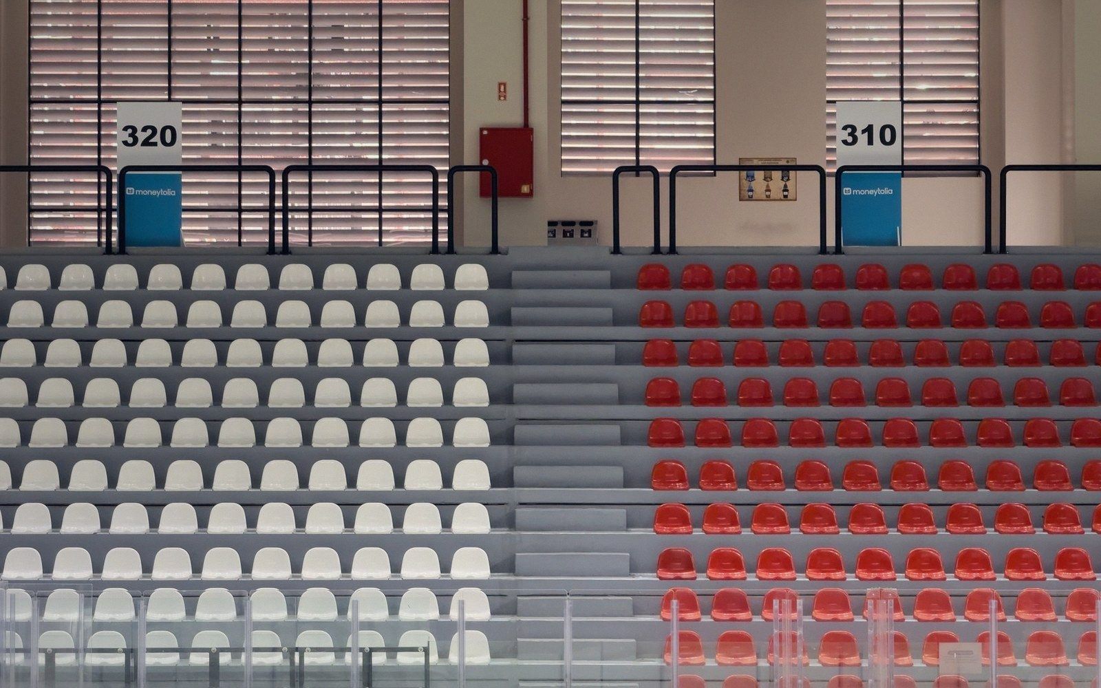 Empty white and red seating sections in a stadium grandstand, numbered 320 and 310