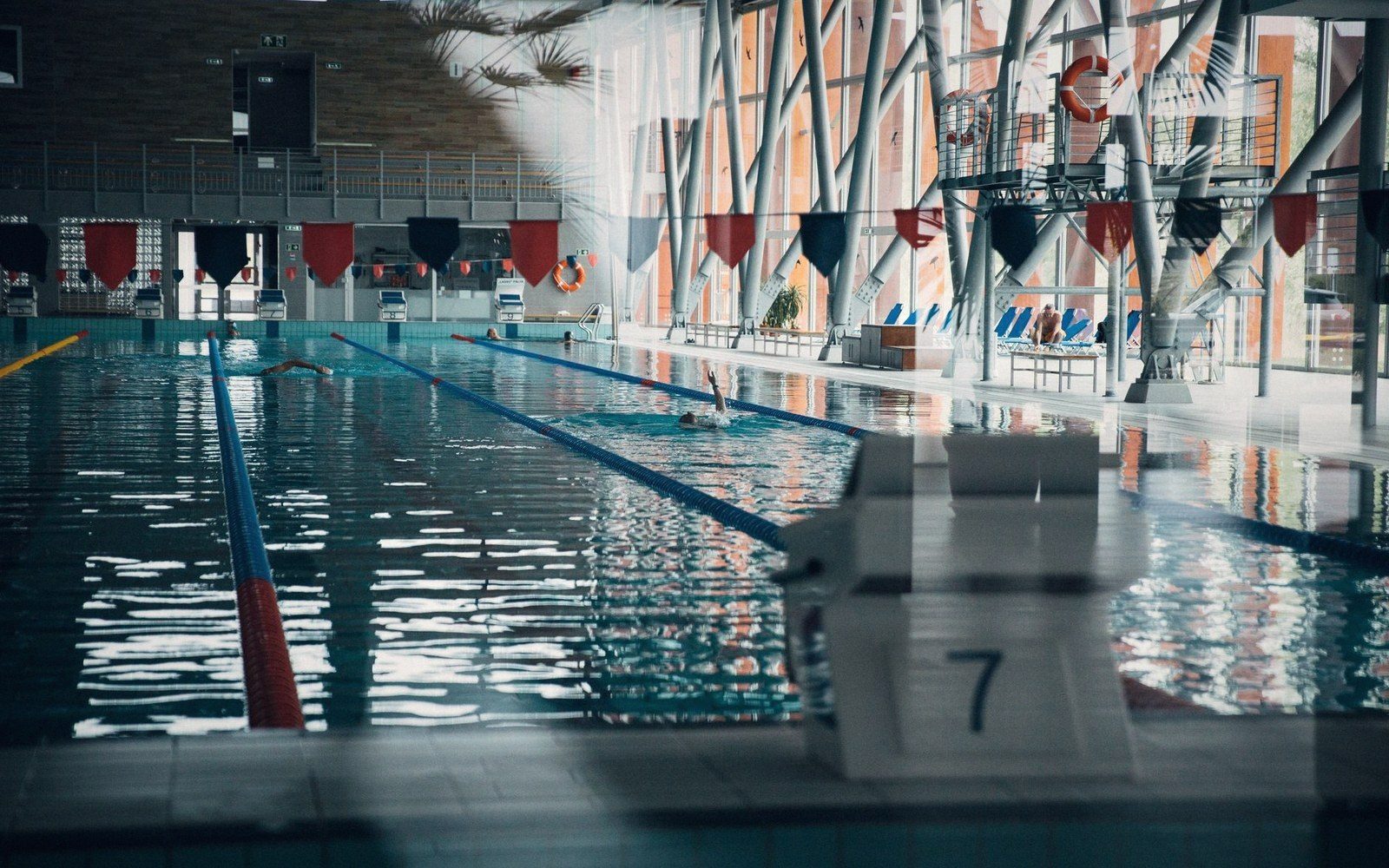 Swimmer crossing lane ropes in an empty indoor competition pool